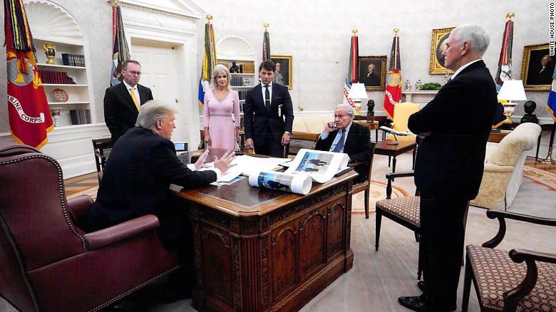 在鲍勃·伍德沃德（Bob Woodward）提供的这张2019年12月的白宫照片中，可以看到唐纳德·特朗普总统在椭圆形办公室与伍德沃德讲话，周围有一些助手和顾问以及副总统迈克·彭斯（Mike Pence）。在特朗普的桌子上放着特朗普和朝鲜领导人金正恩的全貌.jpg