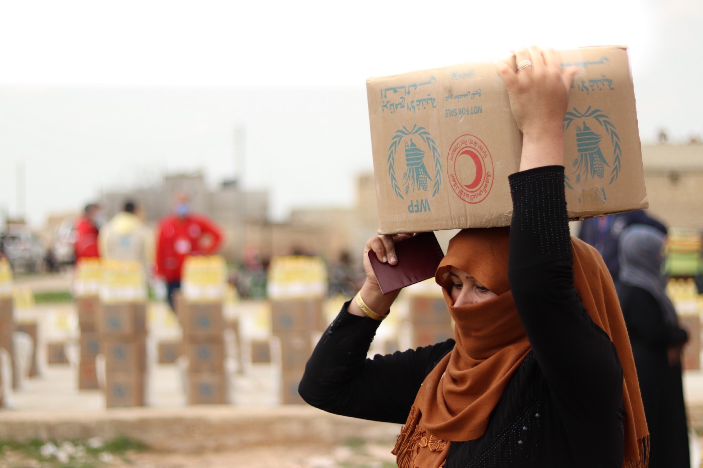 一名妇女在距离叙利亚阿勒颇60公里的Deir Hafer收集食物，粮食计划署正在与叙利亚阿拉伯红新月会合作，向最脆弱的人分发食物，并确保家庭了解COVID-19和安全措施。照片世界粮食计划署.jpeg