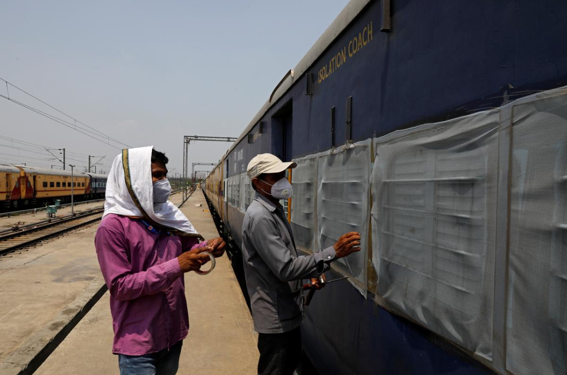 工人们在2020年6月15日在印度新德里的一个铁路货场上，将一辆蚊帐固定在一辆停放的旅客列车上，该列车将装备用于治疗冠状病毒病（COVID-19）的患者，以保护该疾病扩散。（图源：路透社）.png