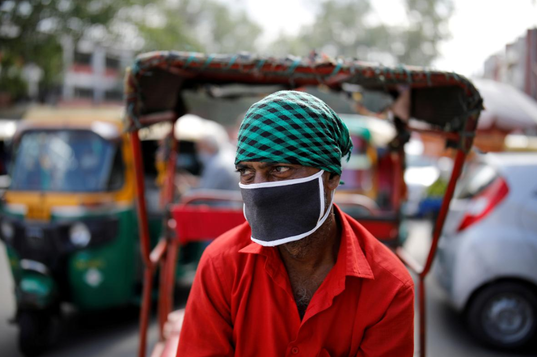 在印度德里的老城区中，一名戴着口罩的人力车夫正在等待客人。（图源：路透社）.png